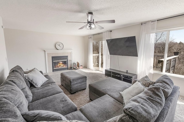 carpeted living area with a tiled fireplace, a healthy amount of sunlight, and a textured ceiling