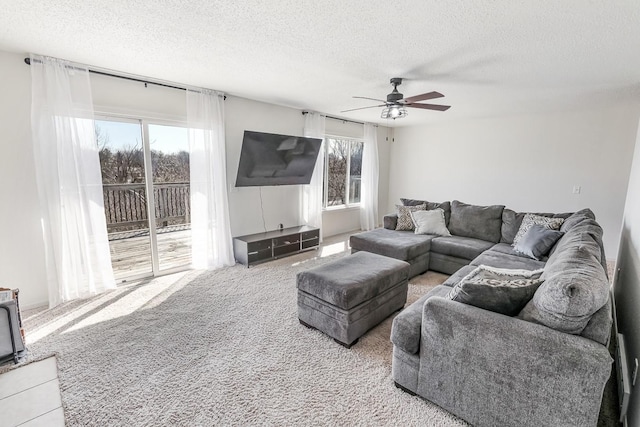 carpeted living area with a ceiling fan and a textured ceiling