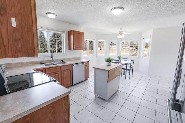 kitchen featuring light tile patterned floors, a sink, light countertops, and stainless steel dishwasher