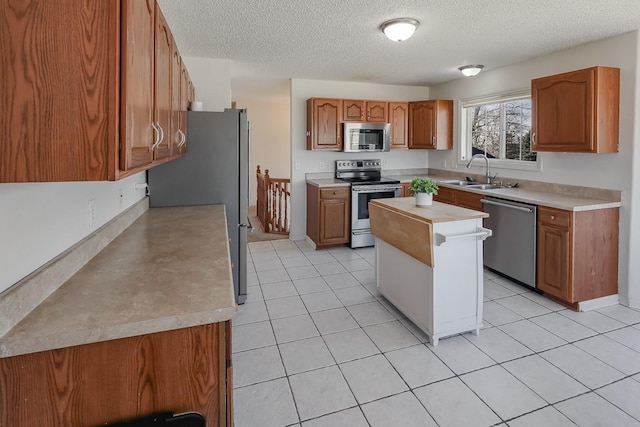 kitchen with brown cabinetry, appliances with stainless steel finishes, light countertops, and a sink