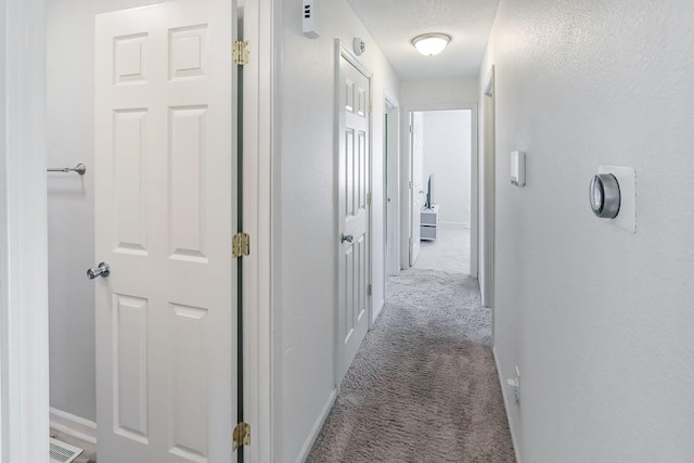 corridor with visible vents, carpet floors, and baseboards