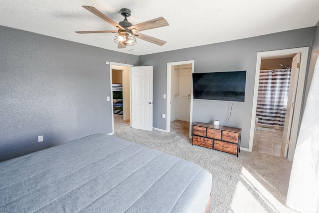 bedroom featuring ensuite bathroom, a textured ceiling, a walk in closet, and carpet