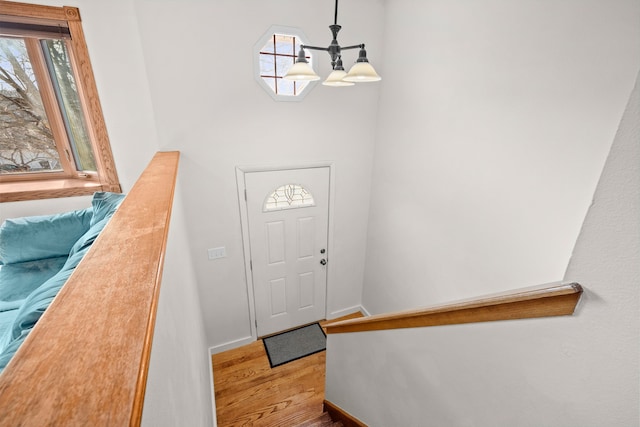 entrance foyer with an inviting chandelier, wood finished floors, baseboards, and a wealth of natural light