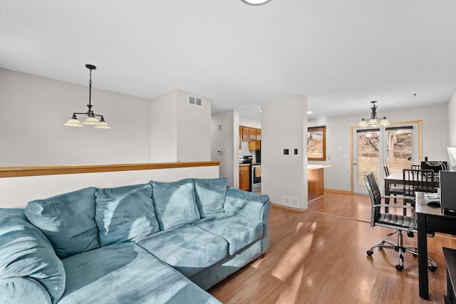 living area featuring visible vents, light wood-type flooring, and baseboards