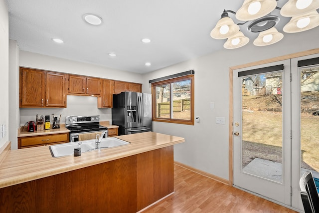 kitchen with light countertops, brown cabinetry, light wood-type flooring, and stainless steel appliances