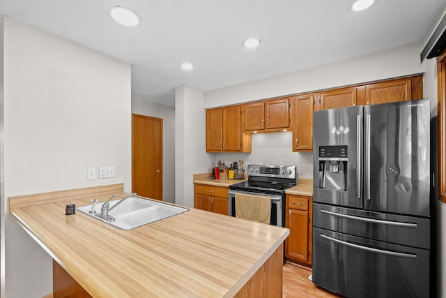 kitchen featuring a peninsula, recessed lighting, a sink, stainless steel appliances, and light countertops