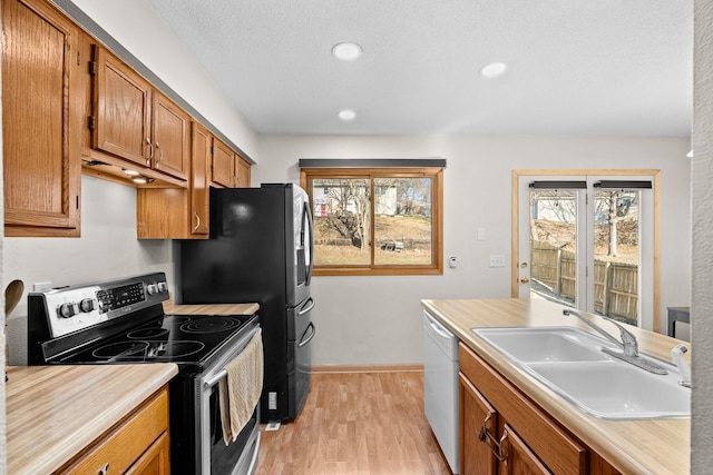 kitchen with light countertops, brown cabinets, stainless steel range with electric stovetop, white dishwasher, and a sink