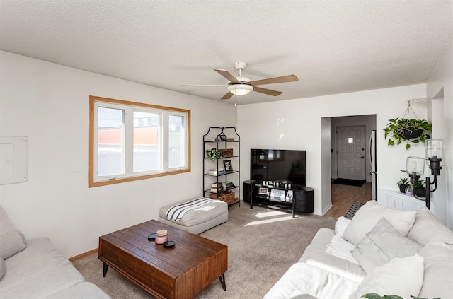 living room with light carpet, baseboards, a textured ceiling, and ceiling fan