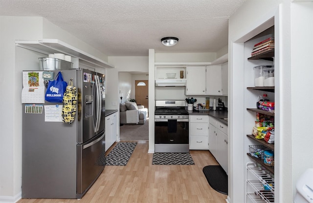 kitchen with dark countertops, under cabinet range hood, stainless steel appliances, white cabinetry, and open shelves