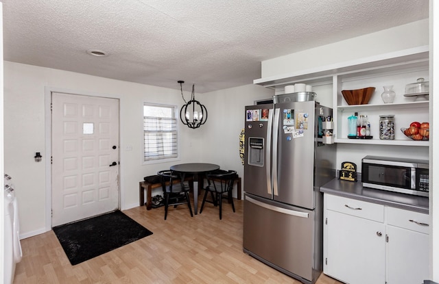 kitchen with white cabinetry, light wood-style flooring, a chandelier, and stainless steel appliances