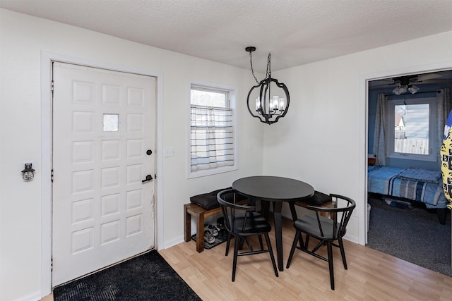 dining space featuring a notable chandelier, baseboards, light wood-style floors, and a textured ceiling