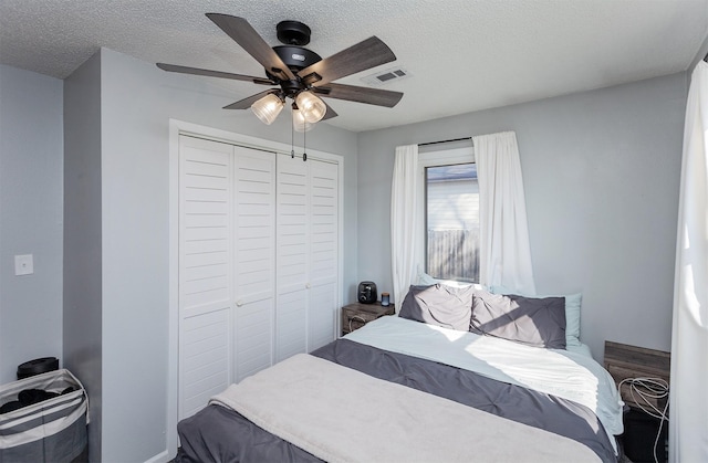 bedroom featuring a closet, visible vents, a textured ceiling, and a ceiling fan