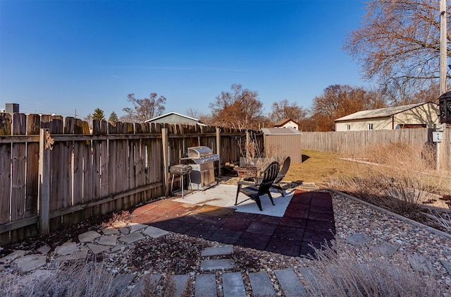 view of patio with a storage unit, an outdoor structure, a fenced backyard, and grilling area