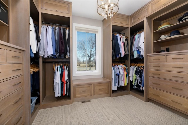 spacious closet with visible vents, light carpet, and an inviting chandelier