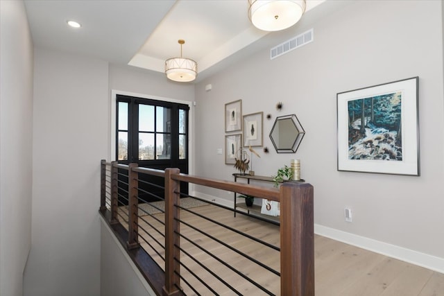 hall featuring light wood finished floors, visible vents, baseboards, an upstairs landing, and recessed lighting