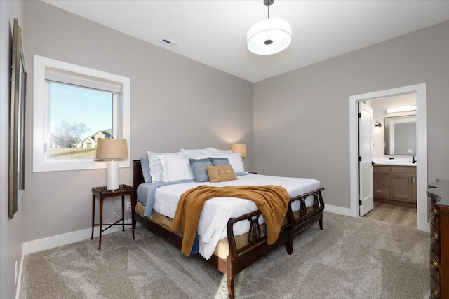 bedroom featuring connected bathroom, baseboards, visible vents, and light carpet