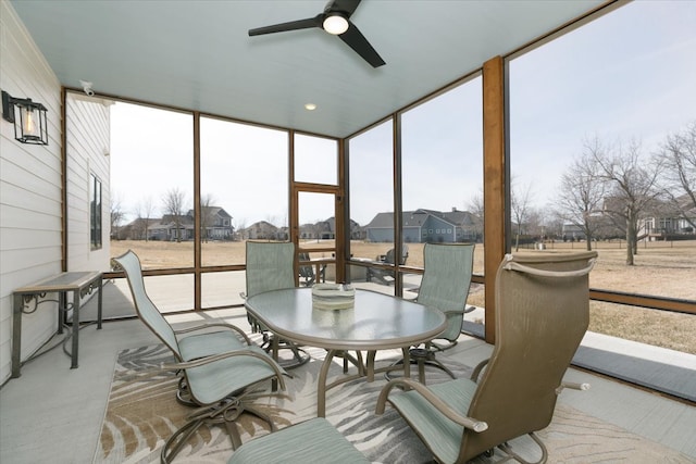 sunroom / solarium with a residential view and a ceiling fan