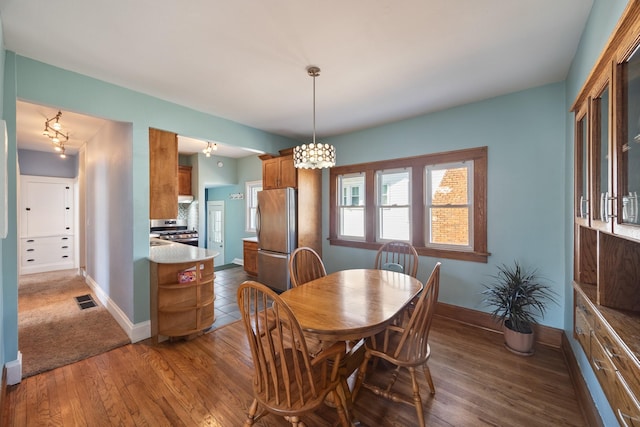 dining room with wood finished floors, visible vents, and baseboards