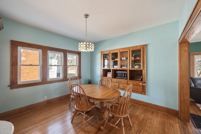 dining area with a chandelier, baseboards, and wood finished floors