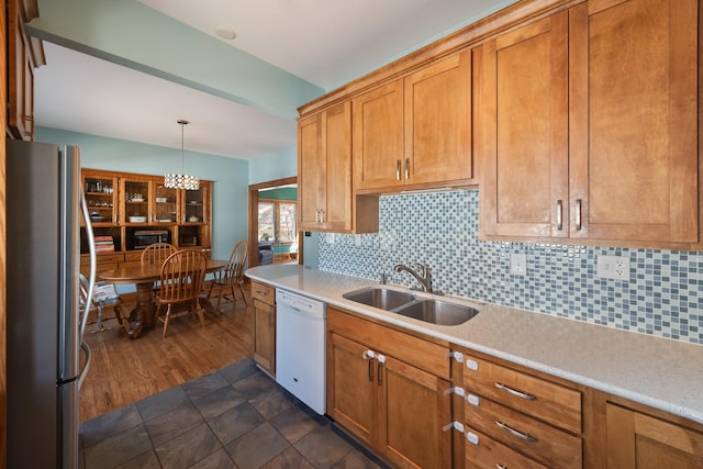 kitchen with a sink, freestanding refrigerator, light countertops, decorative backsplash, and dishwasher