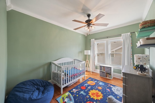 bedroom with a ceiling fan, crown molding, wood finished floors, and baseboards