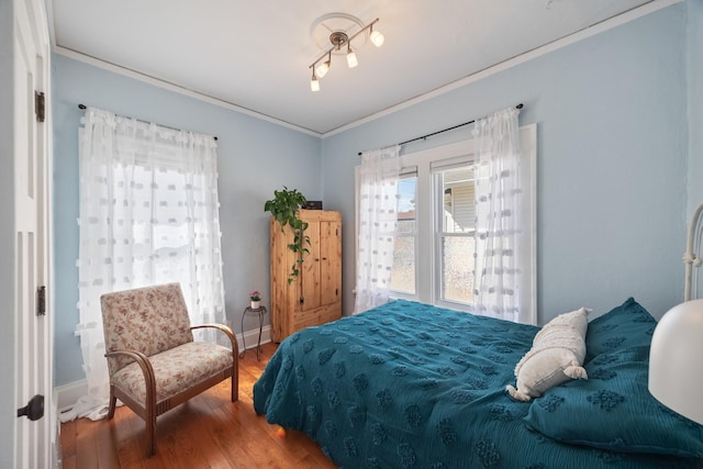 bedroom with crown molding, wood finished floors, and baseboards