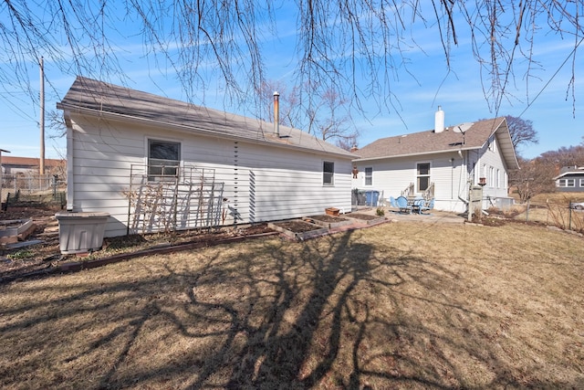 rear view of house featuring a yard, a patio, a vegetable garden, and fence