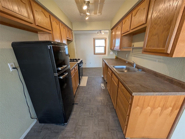 kitchen with a sink, black appliances, a textured ceiling, dark countertops, and a textured wall