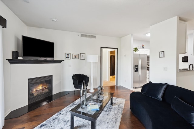 living area featuring a tiled fireplace, wood finished floors, and visible vents