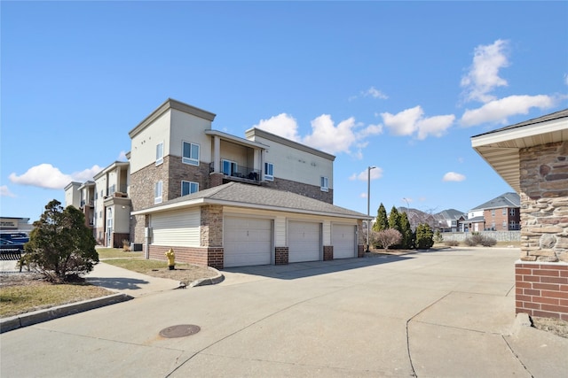 view of property exterior with brick siding, an attached garage, concrete driveway, and a balcony