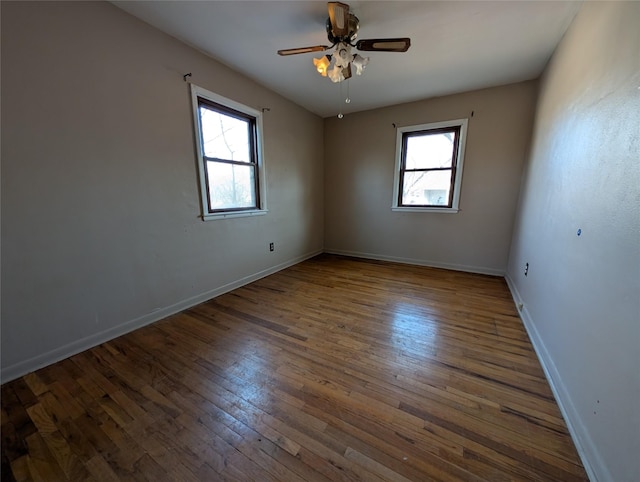 spare room featuring baseboards, plenty of natural light, hardwood / wood-style floors, and a ceiling fan