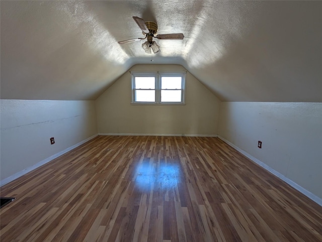 additional living space featuring baseboards, lofted ceiling, a textured ceiling, and wood finished floors