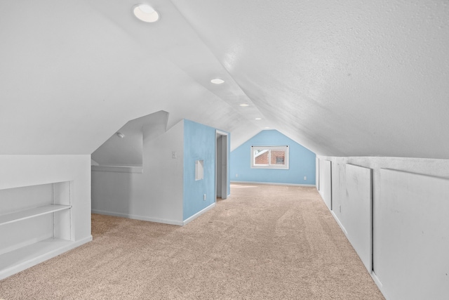 bonus room featuring baseboards, built in features, lofted ceiling, carpet flooring, and a textured ceiling