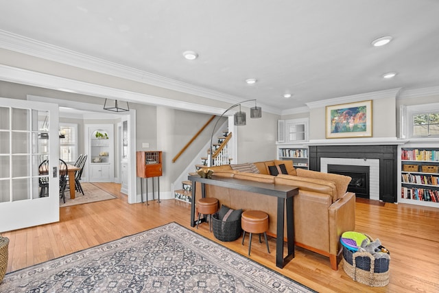 living area with wood finished floors, stairs, and ornamental molding