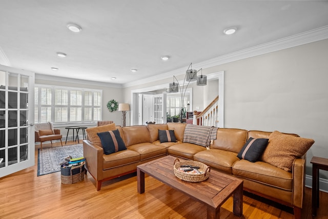 living room with stairway, light wood-style flooring, french doors, and ornamental molding