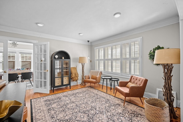 sitting room featuring french doors, baseboards, wood finished floors, and crown molding