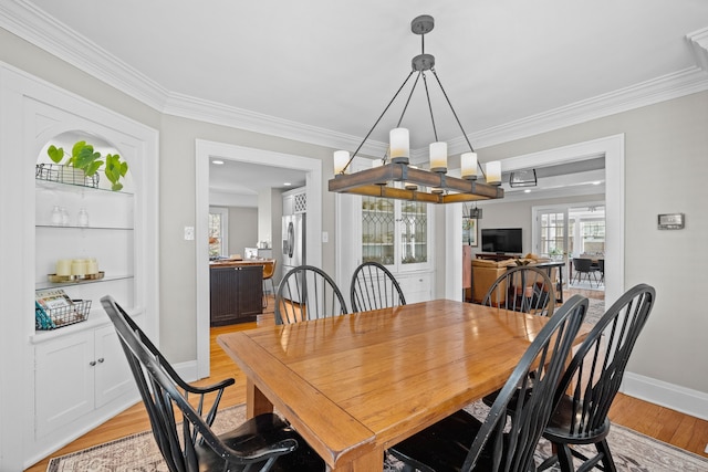 dining area featuring baseboards, crown molding, and light wood finished floors