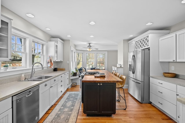 kitchen with a sink, white cabinets, wooden counters, and stainless steel appliances