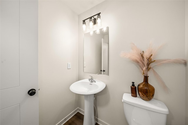 1502 E Girard Ave, Indianola, IA 50125 - bathroom with toilet, baseboards, wood finished floors, and a sink