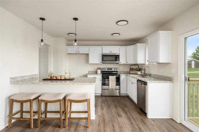 1502 E Girard Ave, Indianola, IA 50125 - kitchen featuring appliances with stainless steel finishes, a sink, dark wood-style flooring, white cabinetry, and a peninsula
