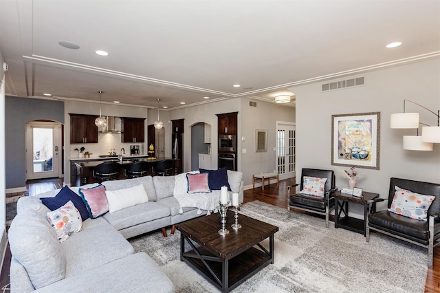 living room with arched walkways, visible vents, recessed lighting, and light wood-style floors