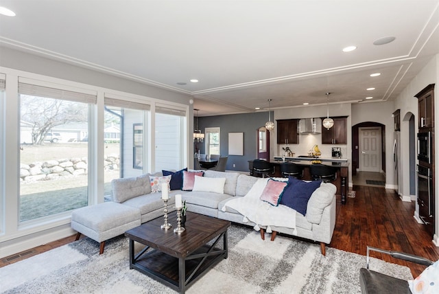 living area featuring visible vents, baseboards, recessed lighting, wood finished floors, and arched walkways