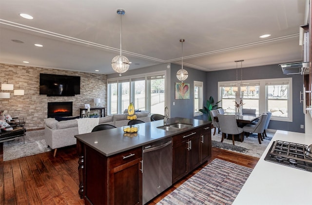 kitchen featuring a sink, decorative light fixtures, dark wood-style floors, appliances with stainless steel finishes, and a stone fireplace