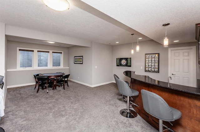 interior space with a textured ceiling, recessed lighting, carpet floors, wet bar, and baseboards