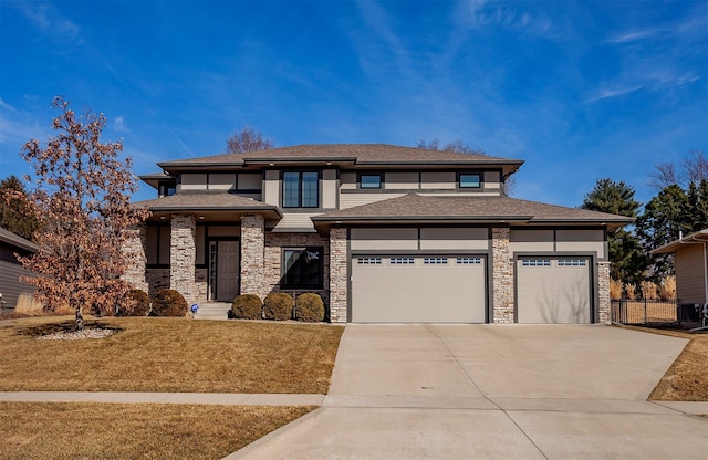 prairie-style house featuring a front yard, fence, driveway, stone siding, and a garage