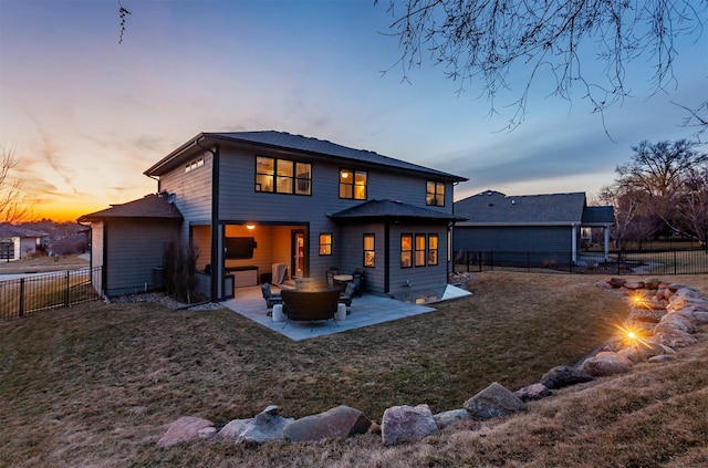 back of property at dusk featuring a lawn, a fenced backyard, and a patio area