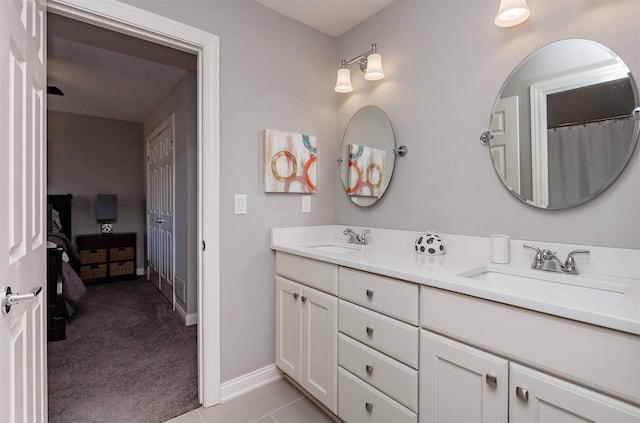 bathroom featuring double vanity, tile patterned floors, baseboards, and a sink