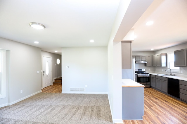 kitchen featuring visible vents, under cabinet range hood, gas range, black dishwasher, and gray cabinets