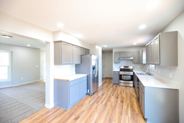 kitchen with gray cabinets, appliances with stainless steel finishes, light countertops, and a sink