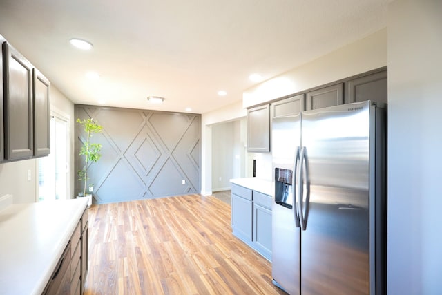 kitchen with recessed lighting, an accent wall, stainless steel refrigerator with ice dispenser, and light wood finished floors